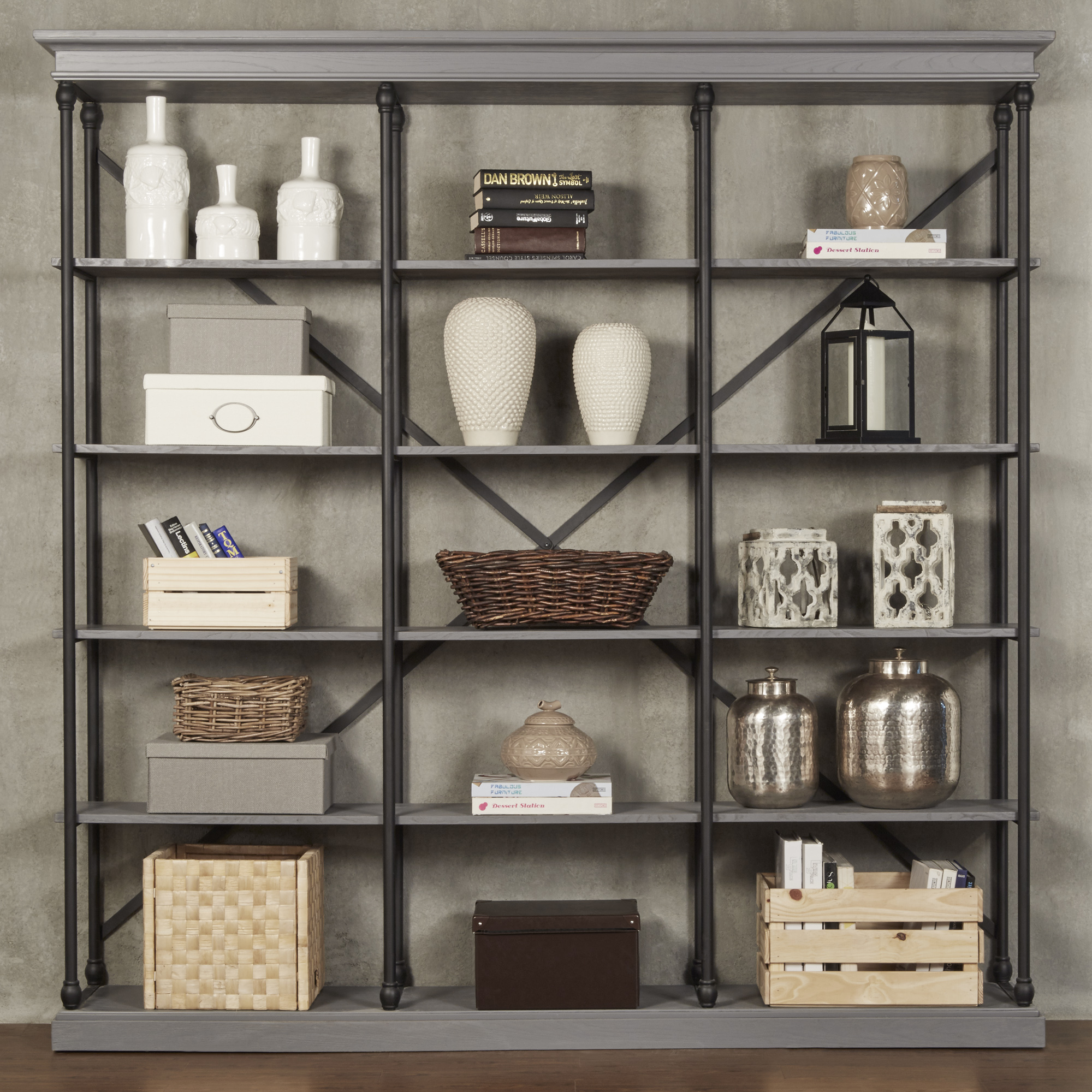This is the iNSPIRE Q Cornice Triple Shelving Bookcase in a grey finish. The shelves are decorated with a multitude of décor of various shades of white, grey, brown, and black. Boxes and baskets provide storage opportunities without creating clutter. 