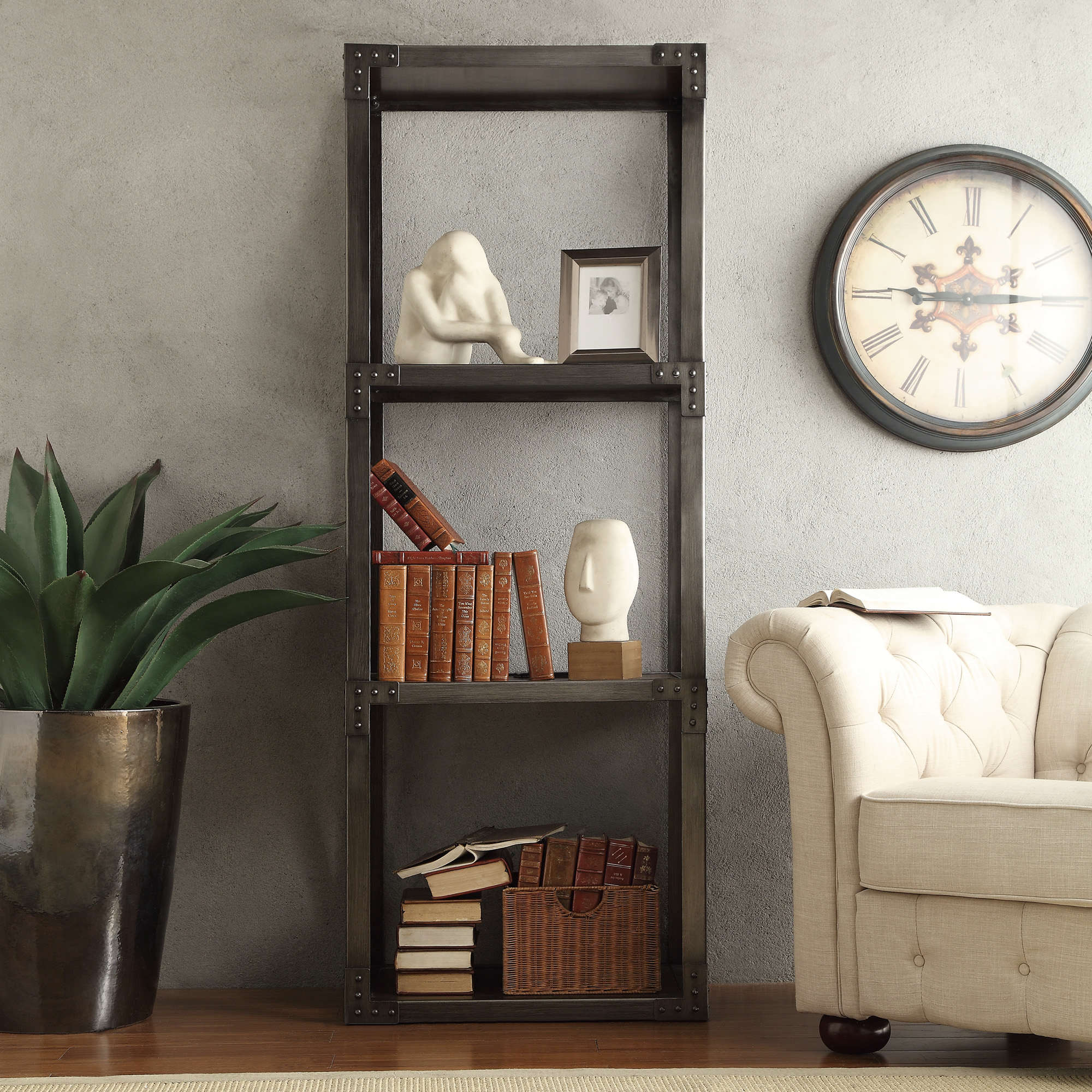 Another image that shows how to decorate a bookshelf. This is one of the all-metal, industrial-inspired bookcases. It is decorated with brown books and brown baskets. But there are also some white-colored pieces of décor that match the beige linen accent chair off to the side. 