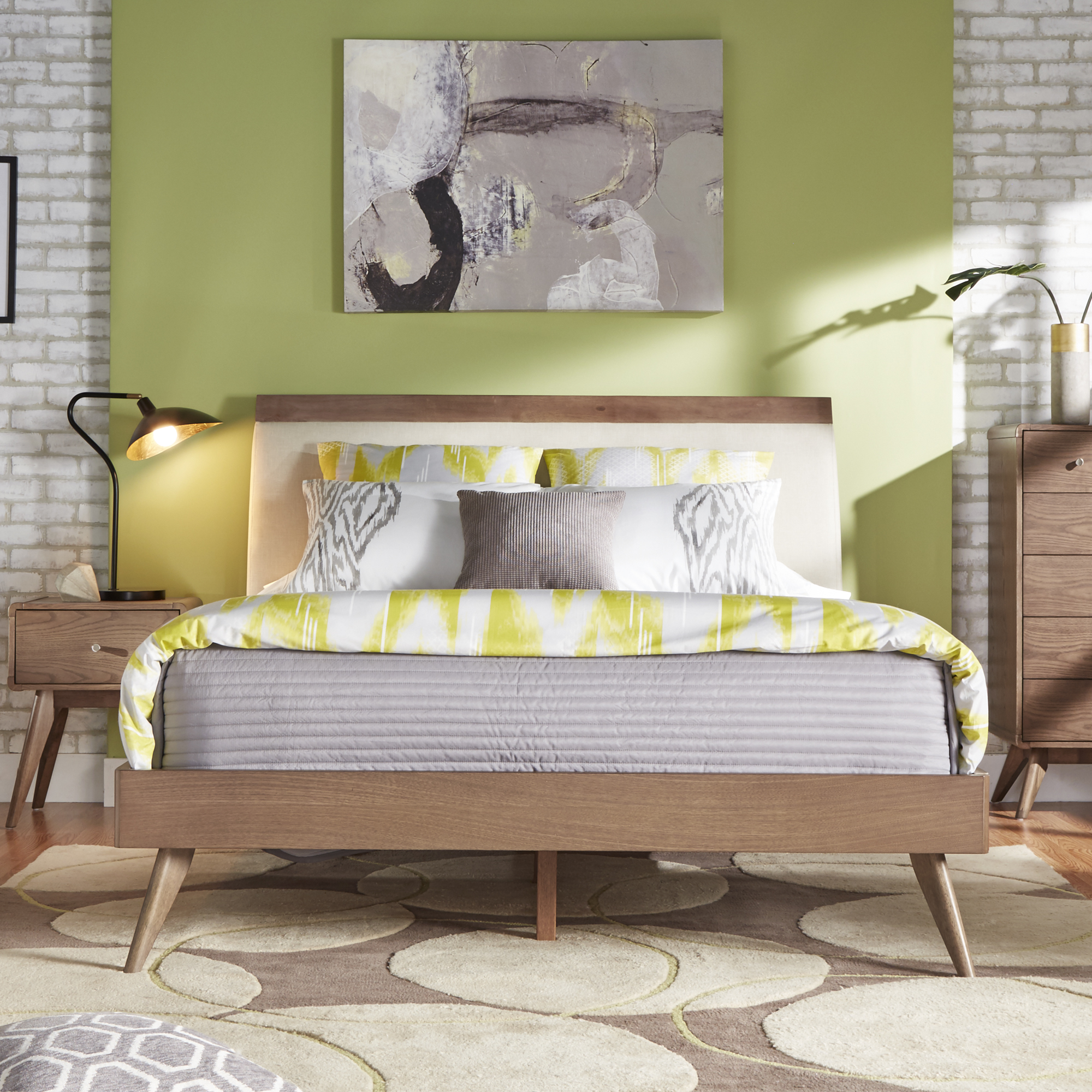 This one of home design trends is all about going bold with paint. This image has a mid-century modern themed bedroom, including furniture with natural wood finishes. What stands out in this image is that the bed is set against a bright green accent wall, which matches the green, grey, and white bedding.