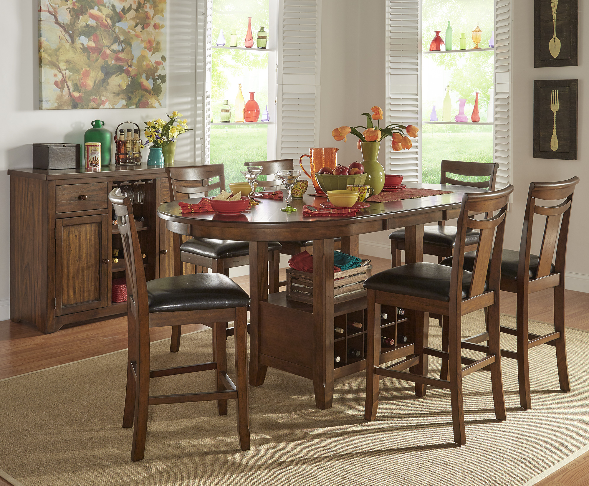 This is a more traditional one of our 10 inspiring dining combinations. It features a dark brown burnished oak dining set, with an oval-shaped dining table and 6 dining chairs. The dining table comes with a built-in wine rack in the base. The dining chairs have dark brown faux leather upholstered seats. The dining table is decorated with red, green, orange, and yellow accessories, perfect for fall.
