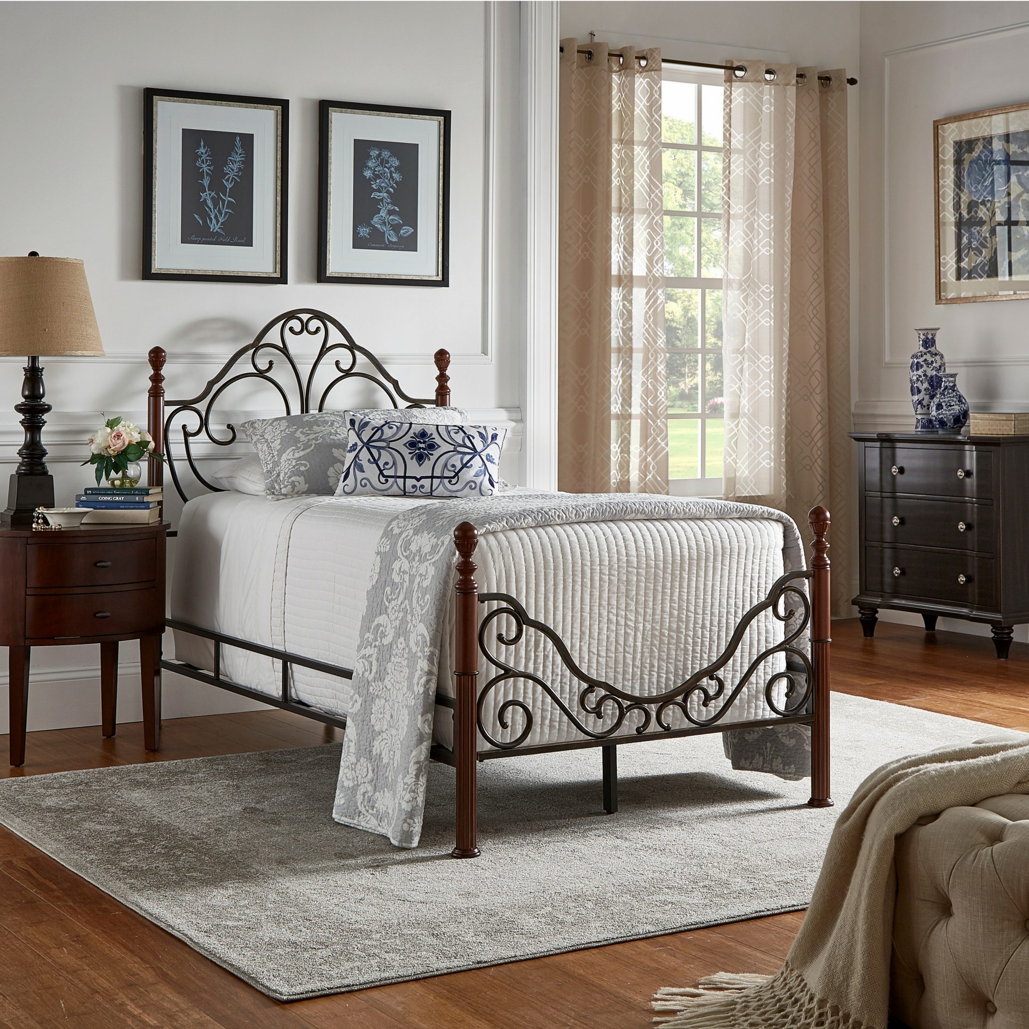 This guest room features a beautiful antique bronze metal bed with beautiful scroll work done on the head and footboards. The bed is dressed with white, grey, and blue bedding with plenty of pillows to go around.