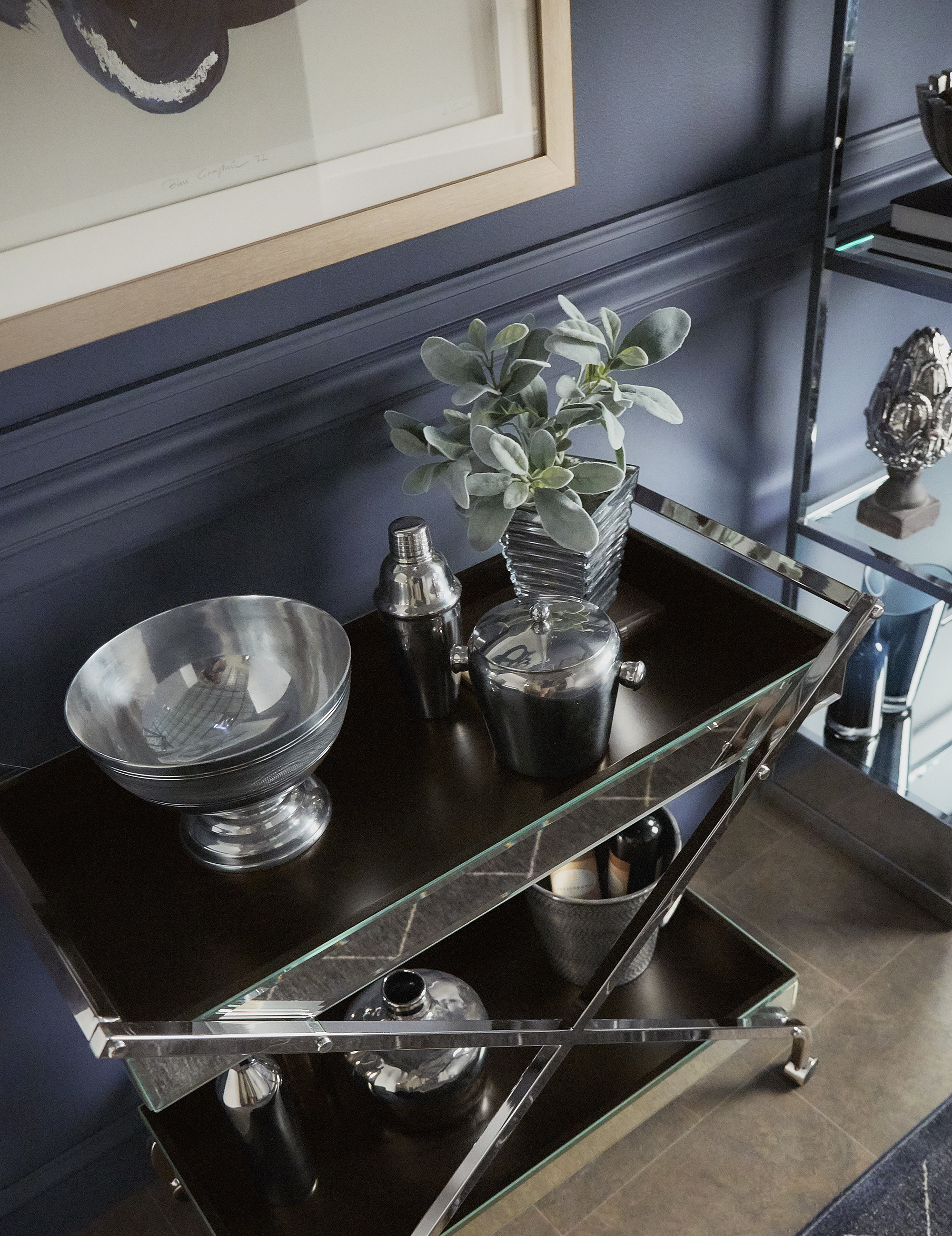 A closer look at how to style a bar cart. This chrome-finished bar cart has mirrored panels and decorated with matching chrome barware.