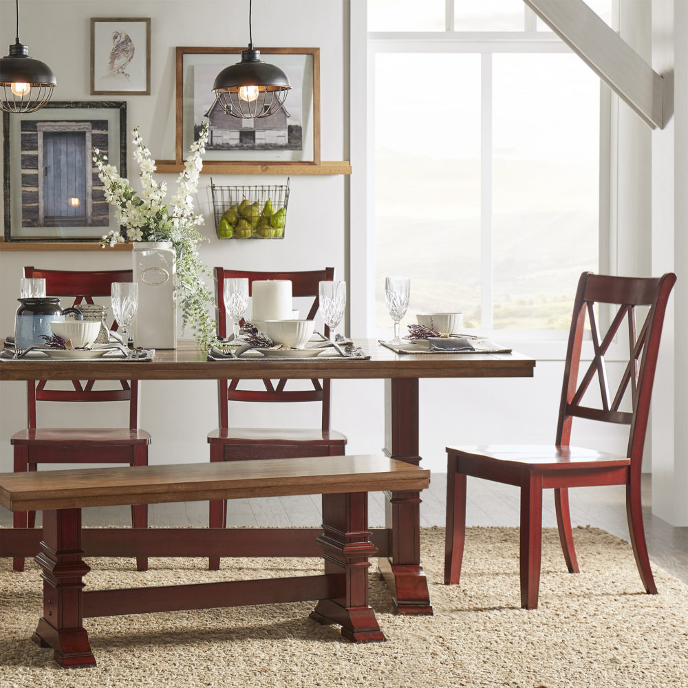 The last of our classic interior design styles focuses on the dining room. This look is perfect for those who love farmhouse style. There is a rectangular dining table with a trestle base and two-tone antique finish (oak top and berry red finish base). There is a matching dining bench and three antique berry red side chairs with double X-backs.