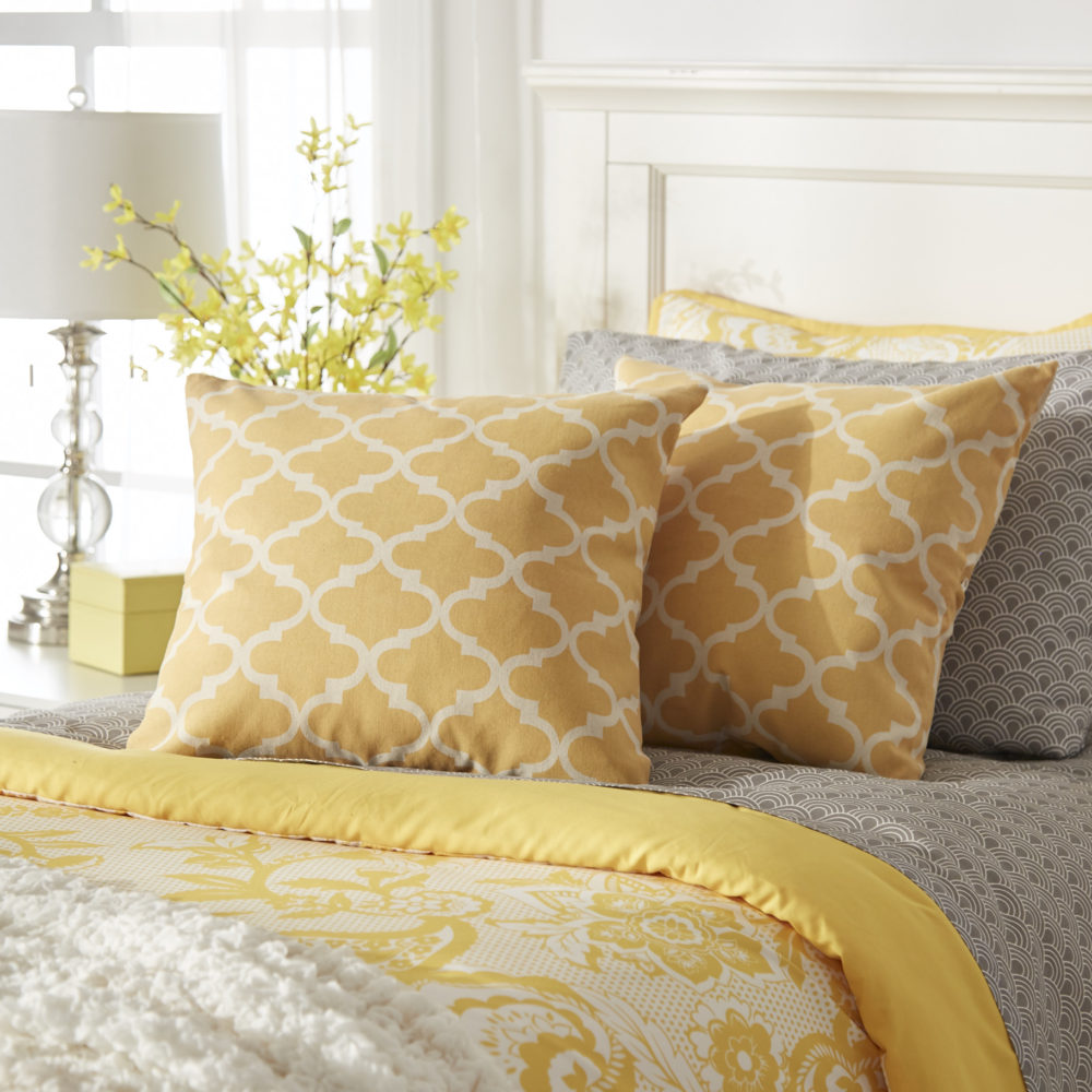 This one way of how to mix textures is similar to the kids bed previously shown. A bed has a white wood panel headboard and grey, white, and yellow bedding. There are various patterns on the bedding, but what stands out most is the yellow Moroccan-print accent pillows set against grey sheets. 