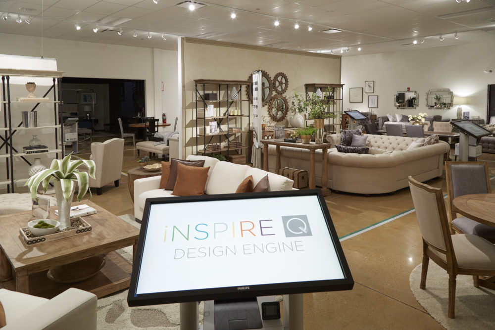 This image shows the completion of our new showroom. It views the room from the entrance but does not capture it in its entirety. We see our iQ Artisan Collection, with several different sofas, loveseats, accent chairs, sectionals, bookcases, and living room tables. In the foreground is the iNSPIRE Q Design Engine kiosk, booted up and ready for use.