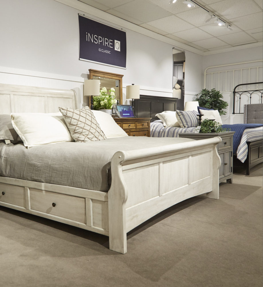 This photo gives us a closer look at the antique white wood sleigh bed. This bed features two drawers built into the bedframe for storage.