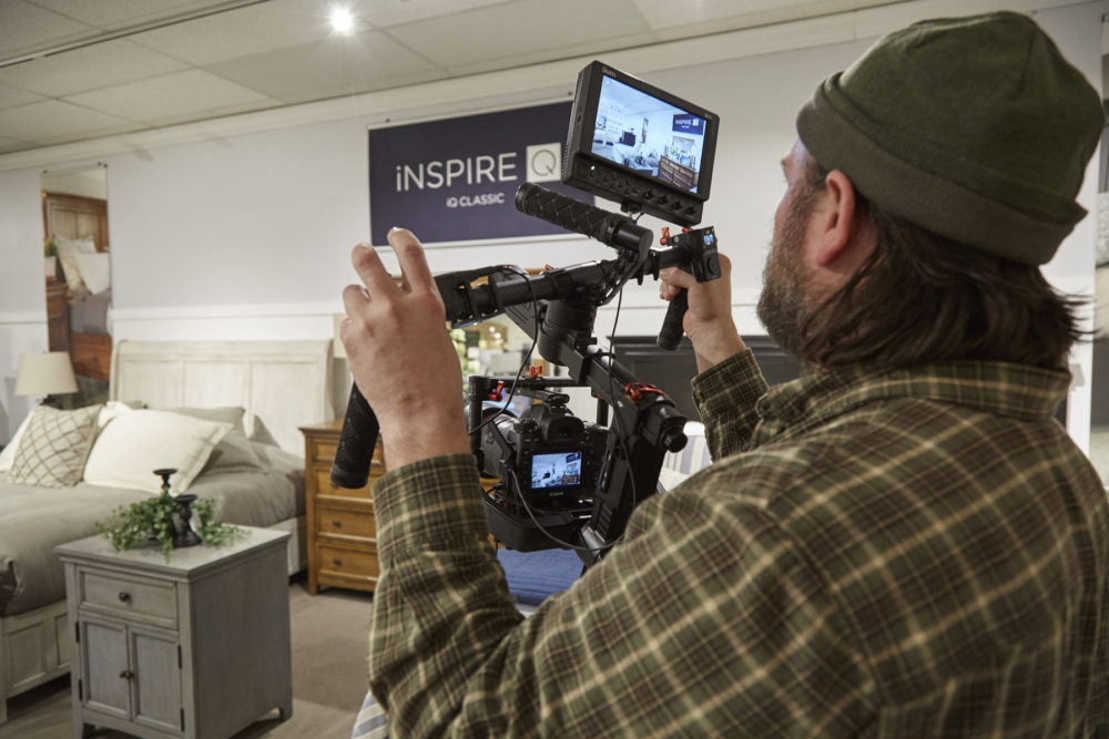 Pictured here is our videographer at work with his camera, looking at the iNSPIRE Q Classic bedroom furniture through the lens.