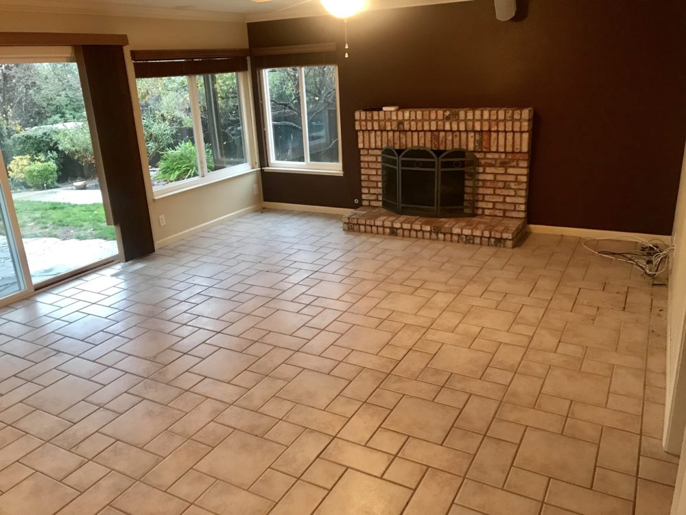 This is another "before" image of our California home makeover. It is of the casual living room in the back of the house. It is an empty room, with white tiled floor, brown painted walls, and an old brick fireplace.