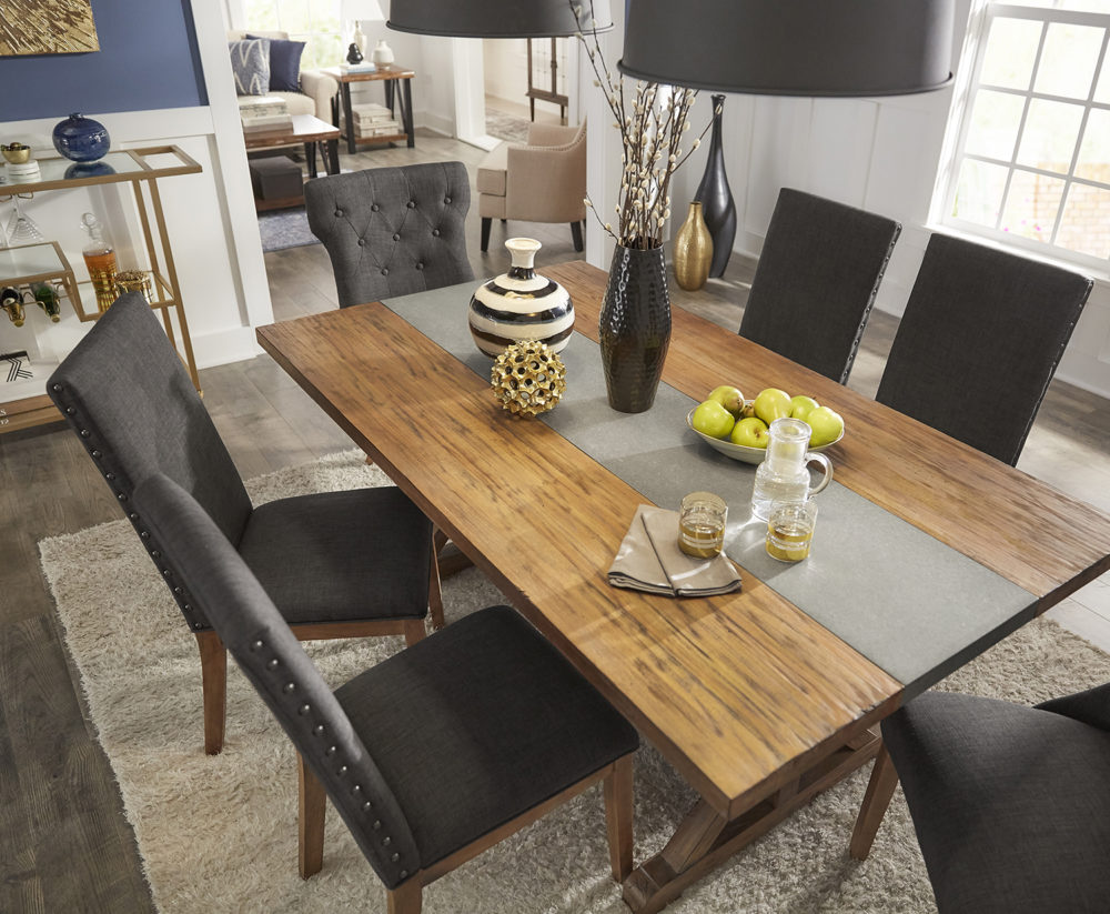 This image shows all the pieces in our modern dining room from an aerial view: the Rustic Pine Concrete Inlaid Table Top Dining Table, four dark grey linen dining side chairs, two dark grey linen button tufted wingback chairs, and a gold metal bar cart. The dining table displays modern décor to suit the theme.