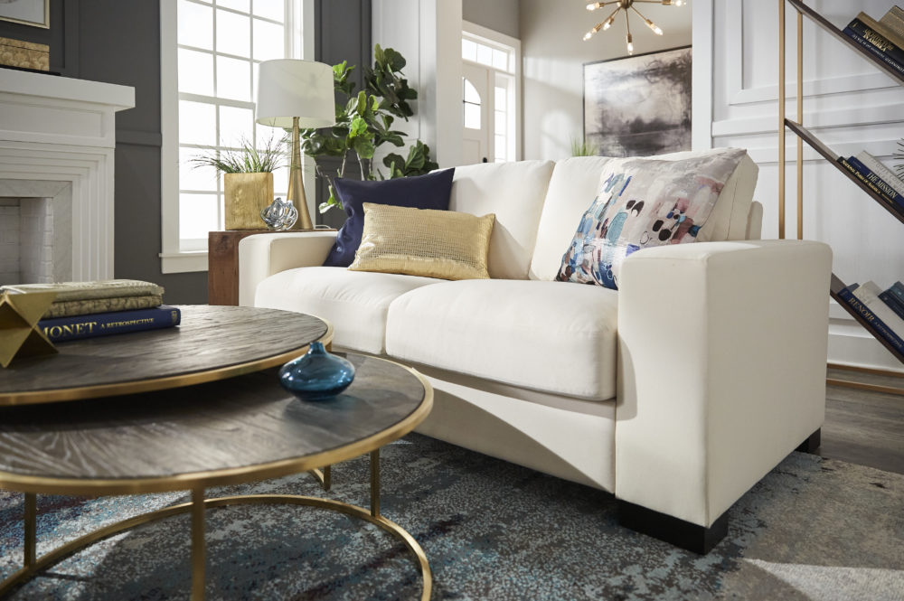 Modern design living room with up close view of white sofa, blue and gold pillows and nesting coffee table