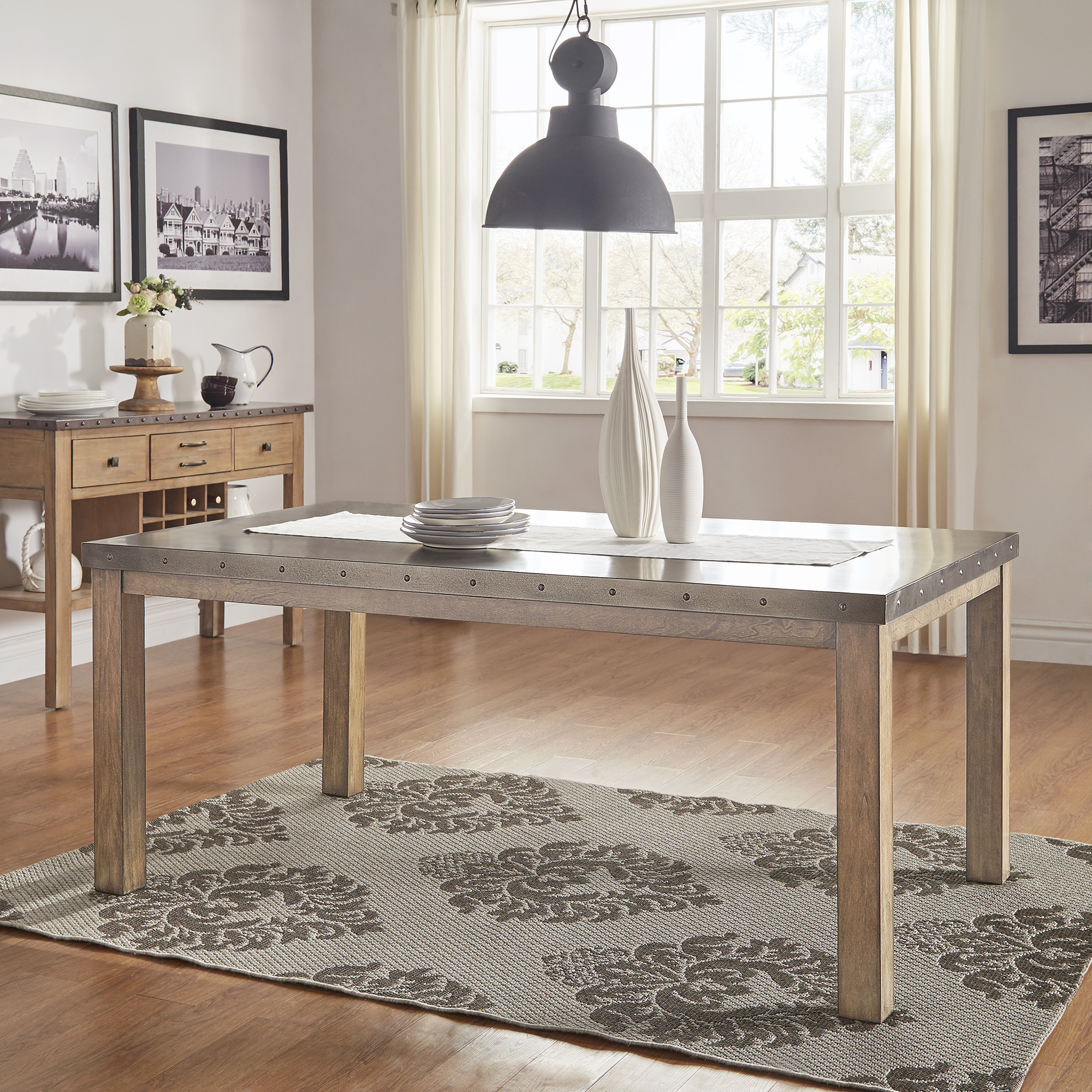 After concrete, we begin to discuss metals. This image focuses on stainless steel, as it features the Stainless Steel Top Rectangle Dining Table by iNSPIRE Q Artisan. The table also boasts a rustic wood finish base, enhancing the industrial, loft-inspired look the table aims to deliver.