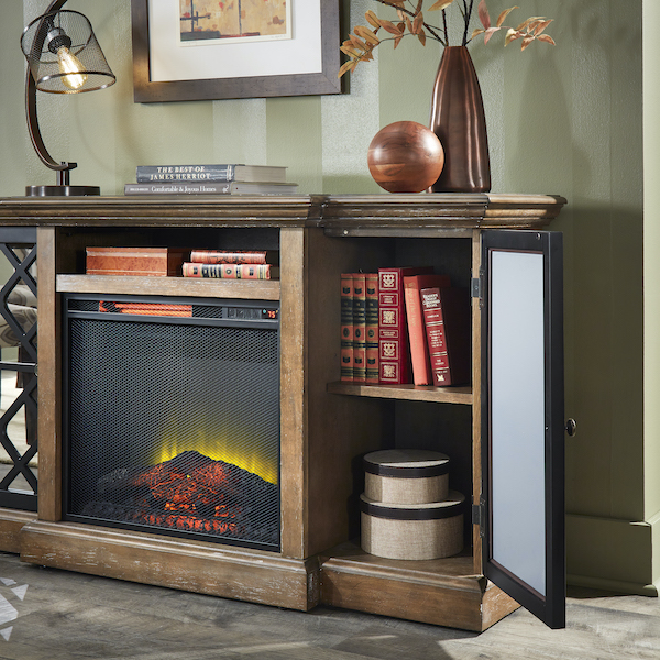 In the last image of our fall home décor trends, we take an even closer look back at the electric fireplace. The electric fireplace is built with two cabinets, one on each side, each behind glass paneled doors. This image shows the door open, revealing an interior shelf with several red books and some brown boxes below.