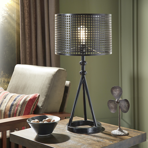 The fall home décor trends is all about the little details. Pictured here is a black metal tripod table lamp atop a wood end table. The end table features two other pieces of décor and is placed next to the Mission-Style Olive Microfiber Accent Chair.